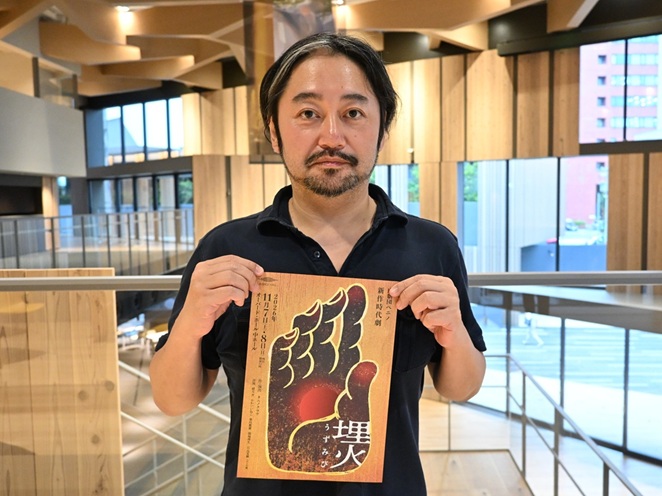 『埋火（うずみび）』の公演チラシを持つ、作・演出を務めるタニノクロウさん。